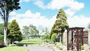 A paved driveway leading to a stone wall with a wooden gate. - The Coach House at Mount Pleasant (Heighington, near Darlington)