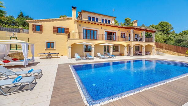 Une grande maison dotée d’une piscine, de chaises longues et d’un patio couvert.