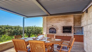 Une terrasse extérieure avec une cheminée en briques, un barbecue et une table à manger avec des chaises.