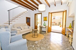 A living room with a staircase, a sofa, a coffee table, and a TV. - Pou davall house (Artà)