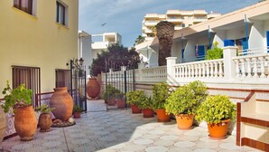A courtyard with terracotta pots, a white balustrade, and a tiled floor. - Apartamentos Bon Aire - 10 (Peguera)