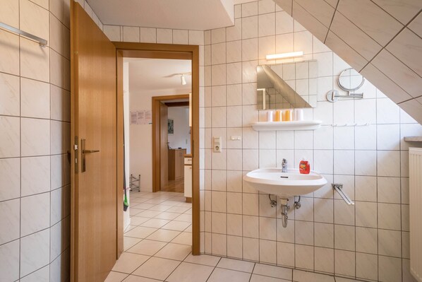A bathroom with a white sink, a mirror, and a shower area.