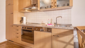 A kitchen with wooden cabinets, a stainless steel oven, a double sink, and a glass-fronted cabinet above the countertop. - Apartment “4-Star Holiday Apartment No. 3” with Wi-Fi, Balcony, Garden & Terrace (Deggenhausertal)