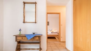 A wooden desk with a mirror, a blue cloth, and a decorative item. A bed is visible in the background. - Apartment “4-Star Holiday Apartment No. 3” with Wi-Fi, Balcony, Garden & Terrace (Deggenhausertal)
