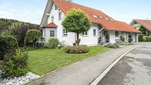 Une maison blanche avec un toit rouge, une pelouse bien entretenue et une allée.