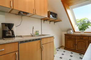 A kitchen with wooden cabinets, a microwave, a coffee maker, and a sink.