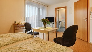 Une chambre d’hôtel avec deux lits, un bureau, une chaise, une télévision et une porte.