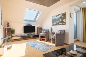 Un salon moderne doté d’une verrière, d’un téléviseur à écran plat, de sièges confortables et d’une grande fenêtre.
