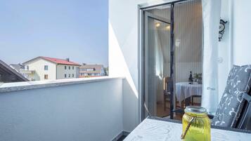 A balcony with a table, a glass jar, and a view of buildings.