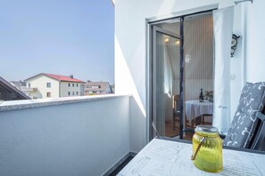 Un balcón con una mesa, un tarro de vidrio y vistas a edificios.