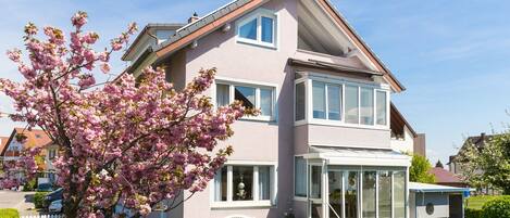 A two-story house with a balcony and a garden.