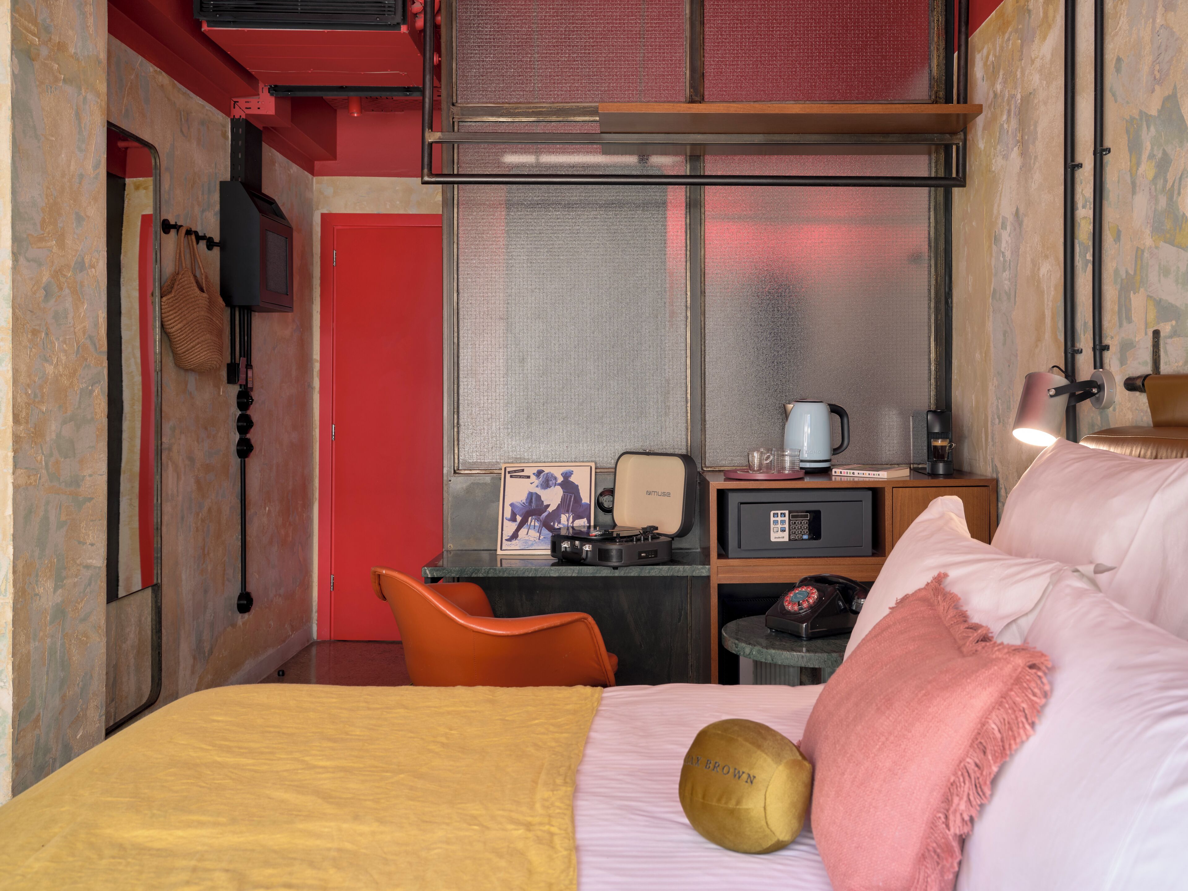 A hotel room with a bed, a desk with a computer, a chair, a microwave, a coffee maker, and a lamp.