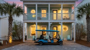 Een tweelaags huis met een balkon op de bovenverdieping, een oprit en een golfkarretje ervoor geparkeerd.