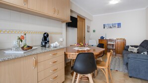 Eine Küche mit Holzschränken, einem Esstisch mit Stühlen, einer Kaffeemaschine und einem Fernseher an der Wand.