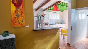 Una cucina moderna con mobili bianchi, un piano di lavoro nero e una lampada a sospensione rossa.