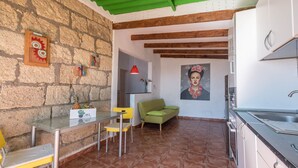 Una cucina con zona pranzo, un divano verde e un quadro appeso al muro.