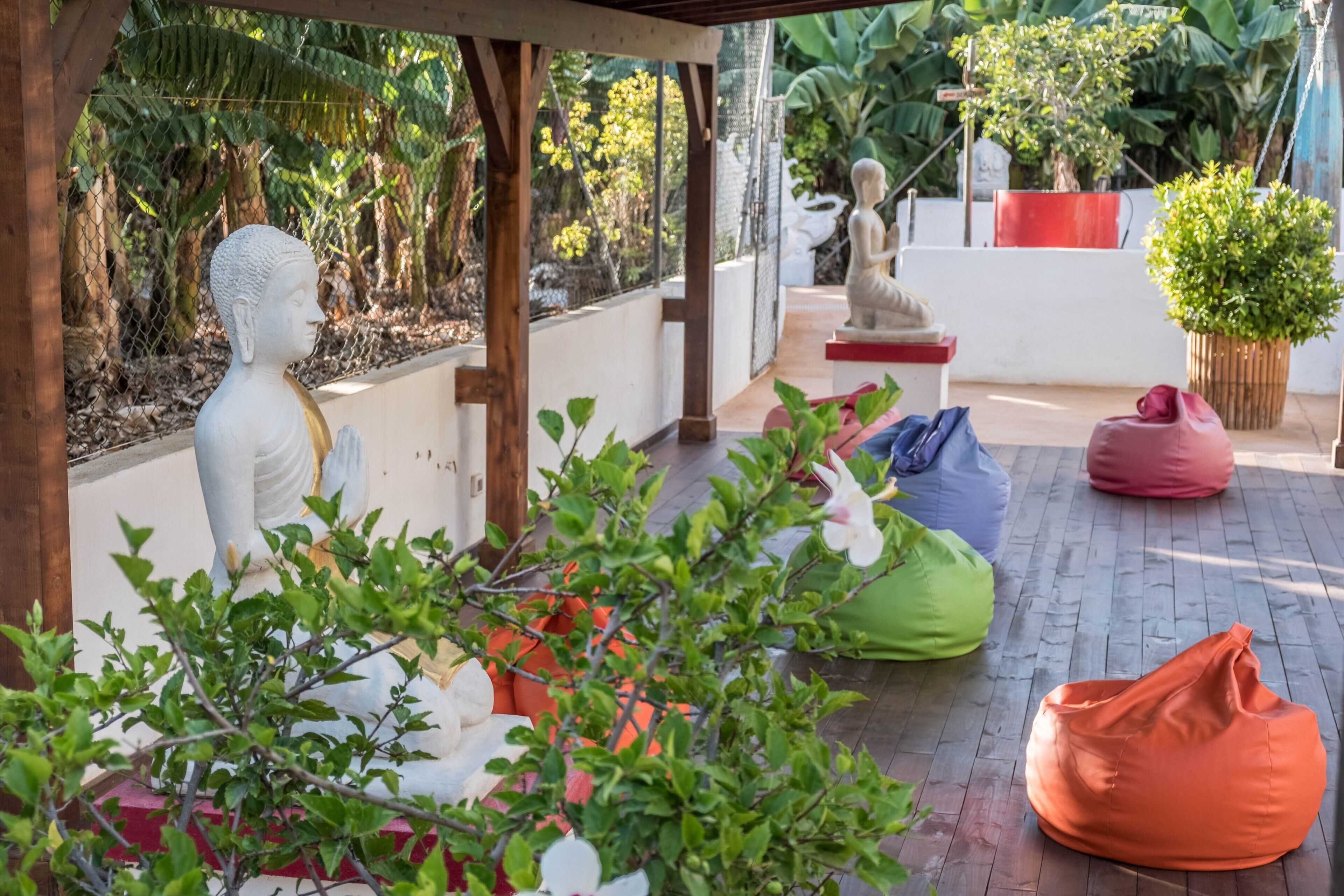 Un espace extérieur abrité comprenant une statue de Bouddha, une statue de Bouddha assis et une plante en pot.