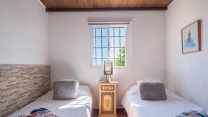 Una camera da letto con due letti, un termosifone, una finestra e un quadro appeso al muro.