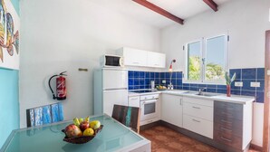 Una cocina compacta con armarios blancos, un microondas, un lavamanos y una ventana con vistas.