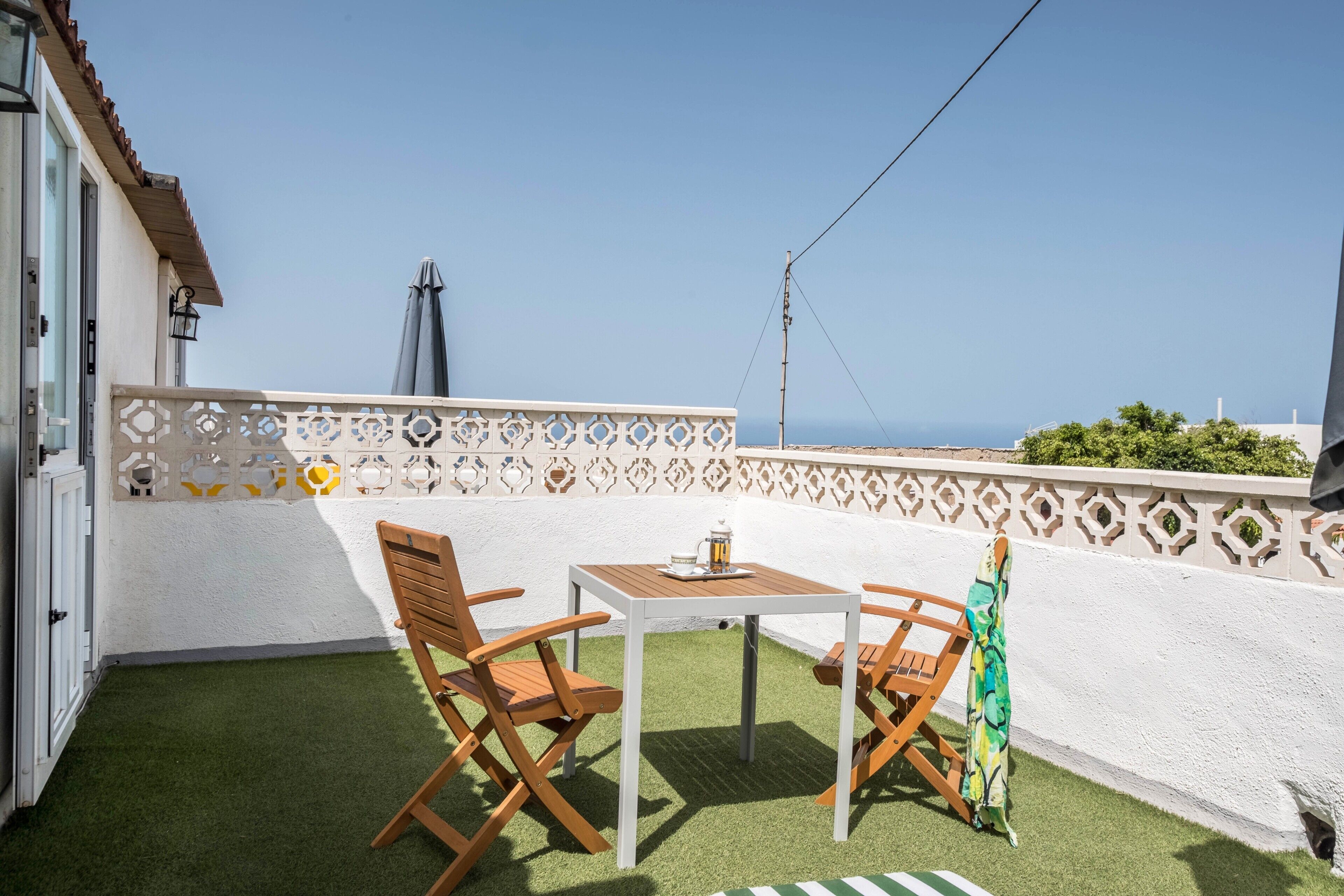 Un balcon avec une table, des chaises et une vue sur la mer.