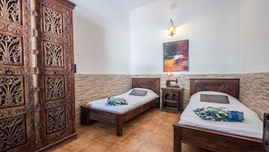 Una habitación con dos camas de madera, una pared de ladrillo, un armario de madera y un cuadro en la pared.