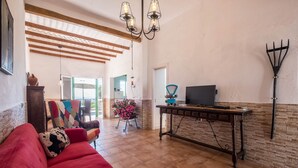 Una sala de estar con un sofá rojo, una mesa de centro de madera, un televisor y una planta decorativa.