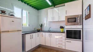 Una cocina con armarios blancos, microondas, horno y lavaplatos.