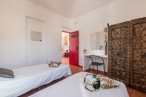 A room with two single beds, a desk with a chair, a red door, and a large wooden door. - Cosy Holiday Home "Casa Sabina" in Alcalá with Terrace, Sea Access and Garden (Guía de Isora)