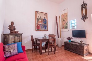 A room with a red sofa, wooden dining table, chairs, a TV, a cabinet, and wall art. - Cosy Holiday Home "Casa Sabina" in Alcalá with Terrace, Sea Access and Garden (Guía de Isora)