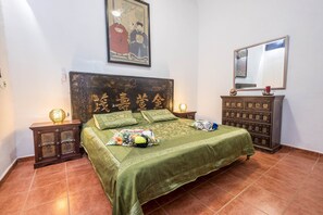 Un dormitorio con una cama grande, un aparador, una mesita de noche con lámpara y un cuadro en la pared.