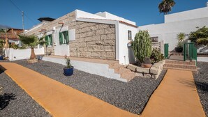 A modern house with a stone facade, green shutters, and a paved driveway. - Cosy Holiday Home "Casa Sabina" in Alcalá with Terrace, Sea Access and Garden (Guía de Isora)