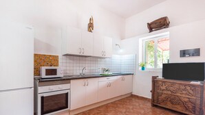 Une cuisine avec des meubles blancs, un four à micro-ondes, un four traditionnel, un évier et un meuble en bois décoratif orné de sculptures.