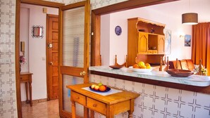 A kitchen with a wooden counter, a sink, and a small table with fruit. - Apartamentos Bon Aire - 13 (Peguera)