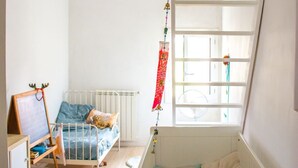 Camera da letto per bambini con culla, letto, scrivania e finestra.