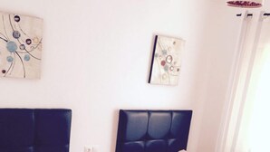 Ein Doppelzimmer mit zwei Betten, einem Nachttisch und einem Wandbild.