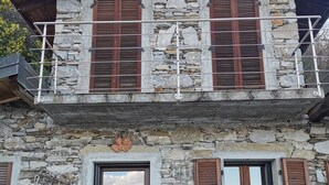 A stone building with wooden shutters and a balcony.