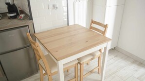 A compact kitchen with a wooden table and chairs, a built-in oven, and a white tiled backsplash.
