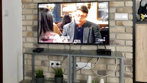 En tv-apparat som är monterad på en tegelvägg, med ett glashyllplan under.