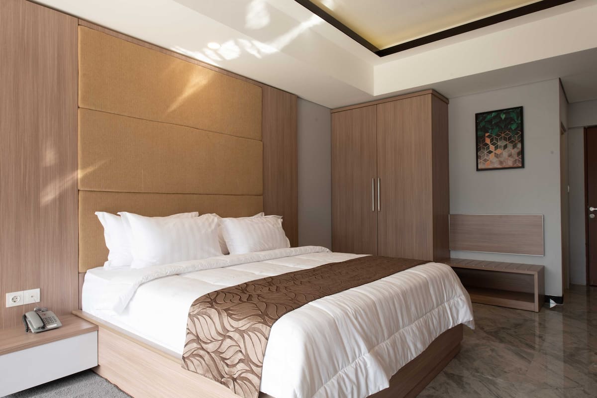 A modern bedroom with a large bed, wooden headboard, and built-in wardrobe.
