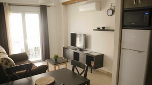 Ein kompakter Wohnraum mit Küchenzeile, Essbereich und einer Couch.