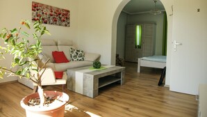 A modern living room with a sofa, coffee table, and a potted plant. - Ferienwohnung Gundacker (Dobersberg)