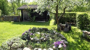 A rustic wooden cabin with a tiled roof, surrounded by a well-maintained garden with a stone wall and flowering plants. - Ferienwohnung Gundacker (Dobersberg)