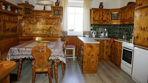 A traditional wooden kitchen with a central island, wooden cabinets, and a dining table set with chairs. - Ferienwohnung Gundacker (Dobersberg)