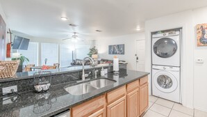 Una cocina moderna con encimera de granito, pileta de acero inoxidable y lavadora y secadora integradas.