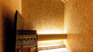 A cozy, wooden-floored room with a bed, a flat-screen TV, and a bench. - eeGee STAY Kamata (Tokyo)