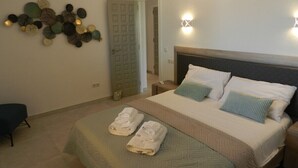 Un llit ben fet amb almoinos, una obra d'art a la paret i una porta en una habitació d'hotel.