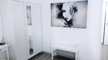 A modern room with a white wardrobe, a bench, and a large abstract painting on the wall.