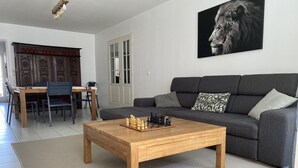 Sala de estar com mesa de centro de madeira, sofá cinza e um tabuleiro de xadrez.