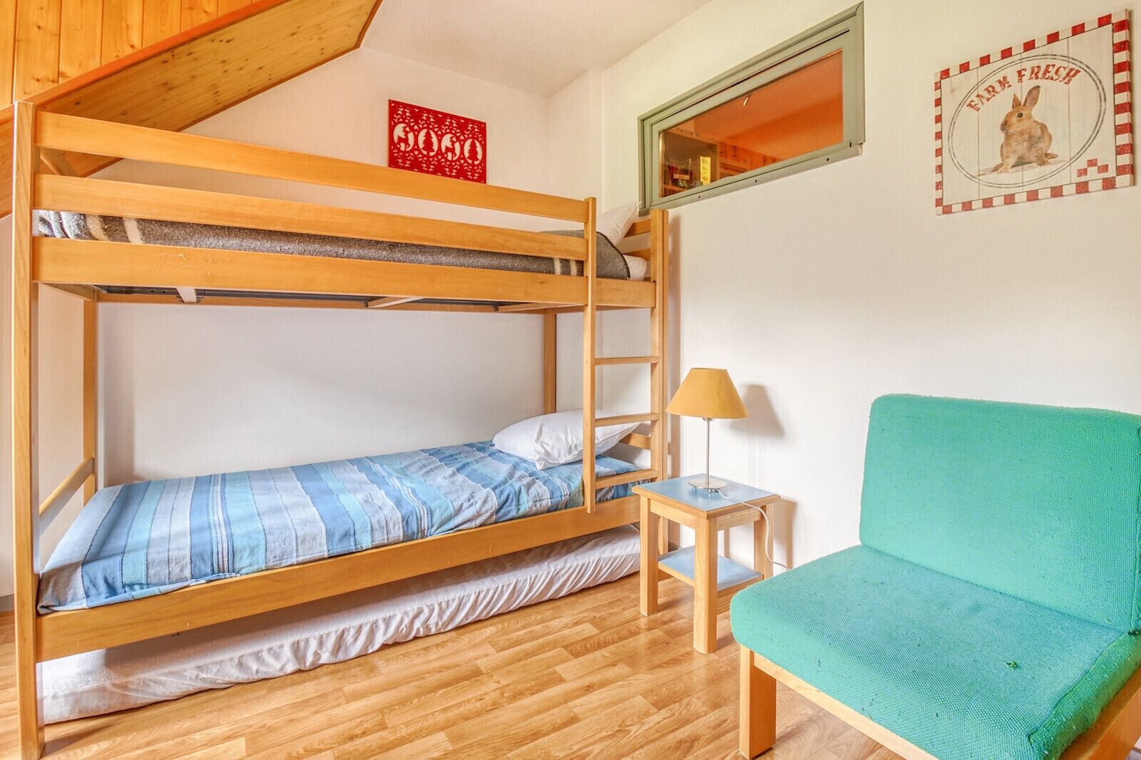 A bunk bed room with a small table and a green chair.