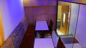 Una habitación pequeña y acogedora con un muro de madera, un banco acolchado, una mesa y sillas.